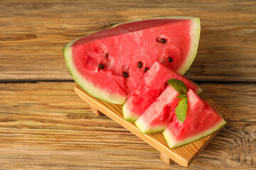 Board with pieces of juicy watermelon on wooden background