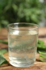 Fresh aloe drink in glass and leaves on wooden table