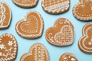 Tasty heart shaped gingerbread cookies on light blue background, flat lay