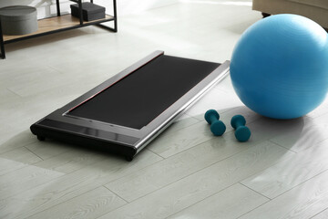 Modern walking treadmill, dumbbells and fitness ball in living room. Home gym equipment © New Africa