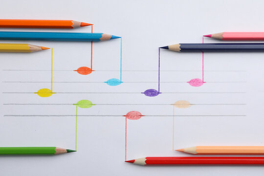 Drawing of musical notes and colorful pencils on white background, top view