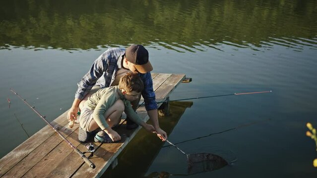 Father and son catching fish with scoop net
