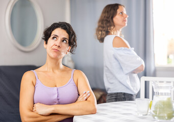 Offended girlfriends having problems in relationship, ignoring each other after home quarrel
