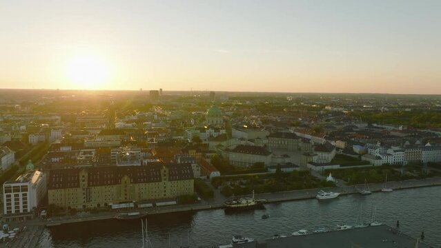Romantic aerial slide and pan footage of historic Amalienborg palace and Frederiks Kirke dome against setting sun. Copenhagen, Denmark