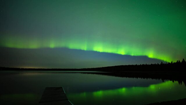 Streams of Aurora dance across a star filled sky and reflect in a calm lake in this time lapse.
