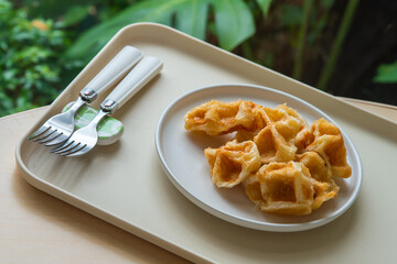 Delicious croissant waffle or croffle on white plate with a  pair of fork, Waffles and Caffles concept, Dessert in cafe concept.  