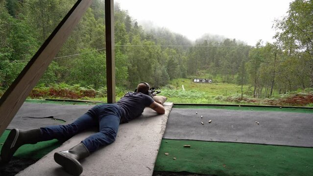 Person with hunting rifle shooting at targets on shooting range - Shots fired and smoke pouring out from muzzle before reloading and continue shooting by himself