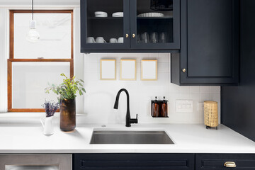 A kitchen detail shot with blue cabinets, a white marble countertop, and cozy decor.