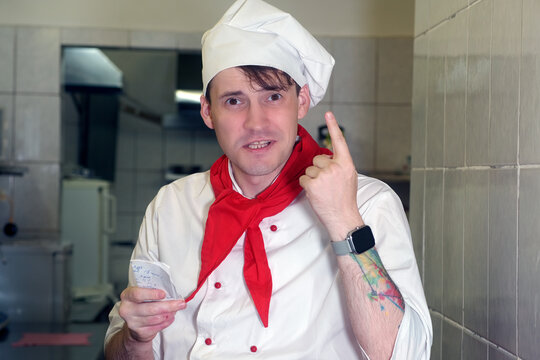 Chef taking order slip in commercial kitchen. Caucasian chef reads out an order for his subordinates in restaurant kitchen