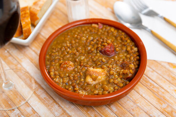Bowl of traditional spanish dish Lentils a la Riojana - thick spicy stew with lentils, vegetables, sausages and meat