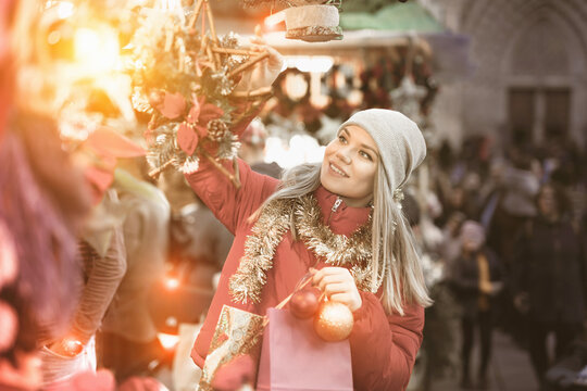 Girl shopping on street selecting decoration for home on Christmas market