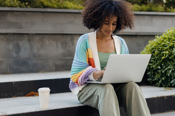 young pretty black woman using laptop outdoor