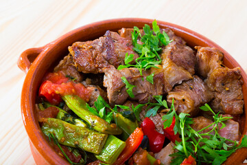 Bulgarian cuisine. Gyuvech - baked meat and vegetable stew served with greens in clay pot