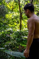 young man, doing yoga or reiki, in the forest very green vegetation, in mexico, guadalajara, bosque colomos, hispanic,