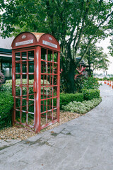 Retro red telephone box along  shady walkway.