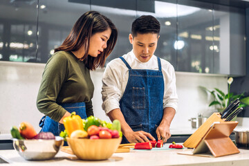 Obraz na płótnie Canvas Young asian family couple having fun cooking together with fresh vegetable healthy food clean on table.Happy couple prepare the food yummy eating lunch in kitchen