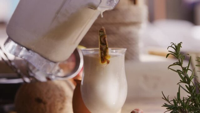 Close up of frozen piña colada cocktail being poured from pitcher on bar counter at tropical resort in mexico