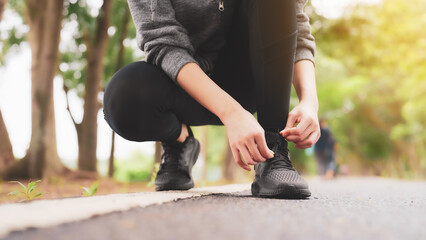 Obraz premium Closeup of woman tying shoe laces. Asian female sport fitness runner getting ready for jogging outdoors in public park