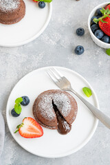 Chocolate fondant lava cake with fresh berries on a plate on a gray background.