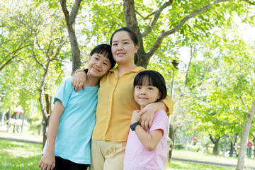 Portrait of young mother and two daughters in blooming spring green park. Mothers day holiday or womans day concept