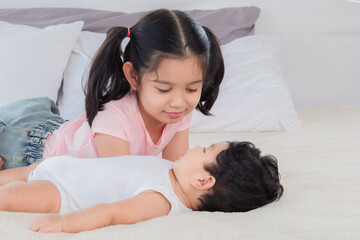 Selective focus happy cute big sister playing with adorable newborn baby brother in morning after...