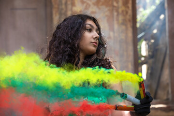 Young girl posing with yellow-green-red smoke bombs in the colors of the Lithuanian flag