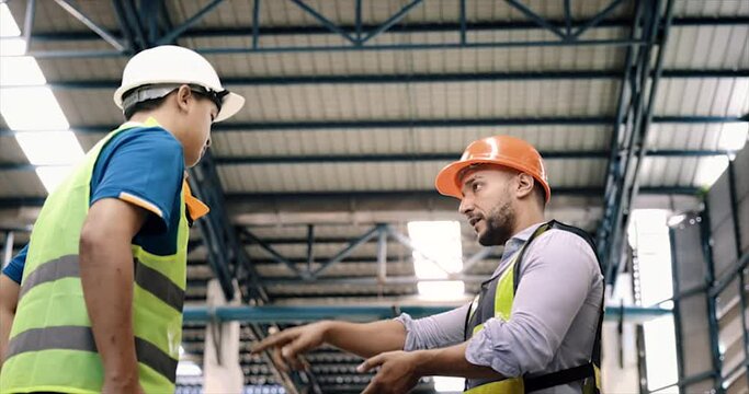 Manager, staff or boss to talking, discussion with worker, employee. Group of people in warehouse, factory with safety helmet, vest. Concept for industry, job, meeting, work training and teamwork.
