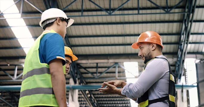 Manager, staff or boss to talking, discussion with worker, employee. Group of people in warehouse, factory with safety helmet, vest. Concept for industry, job, meeting, work training and teamwork.
