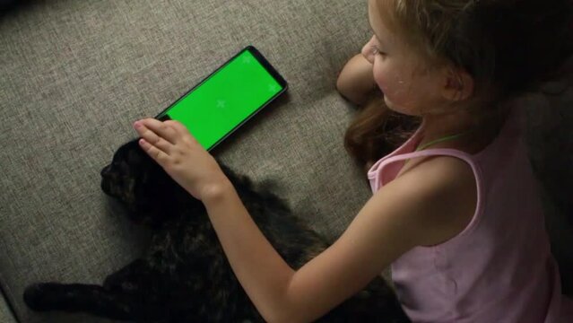 A Child With A Cat Looks At The Phone. Mobile Phone In Children's Hands. Chromed Green Screen. View Over The Shoulder. View Children's Internet Content. Video