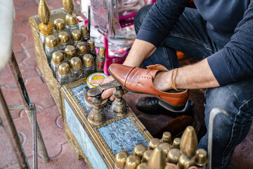 Ancient method of shoe cleaning. Man cleans shoes with help of shoe polish on street, close up.
