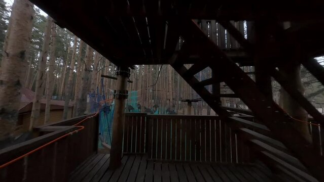 Flight along an empty zipline track in an amusement park in the forest among the trees. Evening. FPV drone view.
