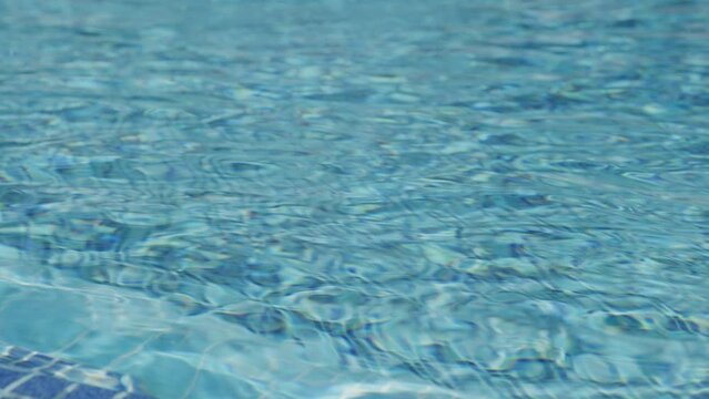 Static Close up shot of rippling pool water with blue tile flooring in sunny day