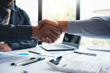 Business people shaking hand to agree to enter into a joint venture agreement to do business together in a new business.