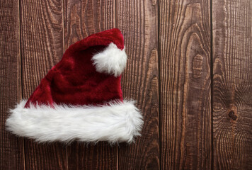 Obraz na płótnie Canvas Red Santa Claus hat isolated on wooden background. Space for text. Flat lay.