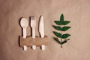 Set of Eco friendly bamboo cutlery with green foliage on brown paper background.