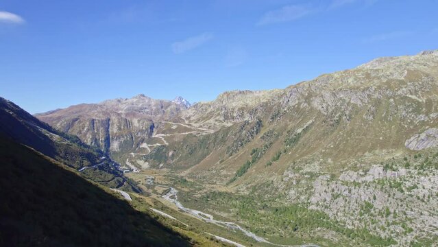 Aerial view of famous Swiss mountain pass Furkapass at 2436 meters above sea level with mountain village Gletsch on a sunny late summer day. Movie shot September 12th, 2022, Furka Pass, Switzerland.