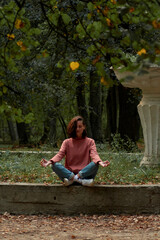 A woman in Casual clothes does yoga in an old park