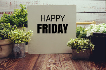 Happy Friday text message with artificial plant decoration on wooden background