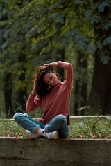 A woman in Casual clothes does yoga in an old park