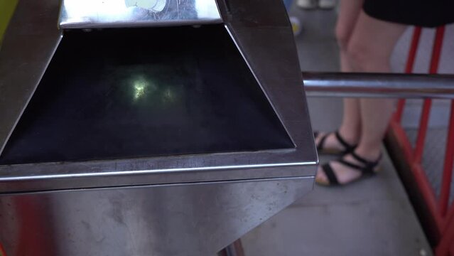 Beautiful girl pass the electronic turnstile with paper ticket entering amusement park. Entrance through turnstile to subway. Validator or ticket control. Contactless reader at gates.
