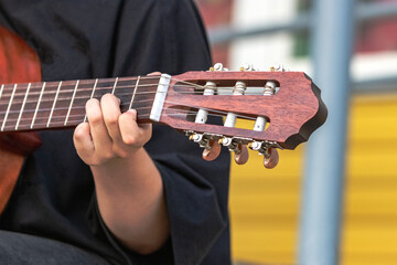 A street musician plays the guitar. Close-up of hands plucking chords. Guitar neck.
