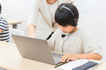 パソコンでプログラミングの授業をする先生と子供（日本人）
