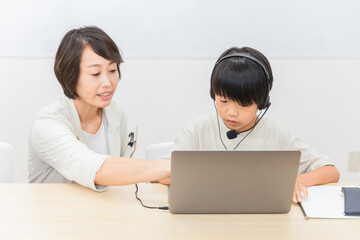 パソコンスクールで使い方を教える講師と子供（日本人）
