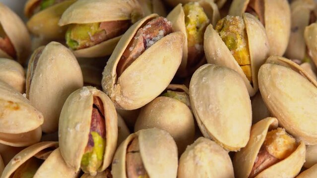 Roasted pistachios rotate on a black background. Salted pistachio nuts for beer background close up. Vegan Healthy food high protein. Dietary nutrition. Concept of nuts.