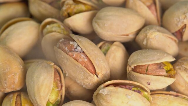 Hot roasted pistachios rotate with stream smoke. Salted pistachio nuts for beer background close up. Vegan Healthy food high protein. Dietary nutrition. Concept of nuts.