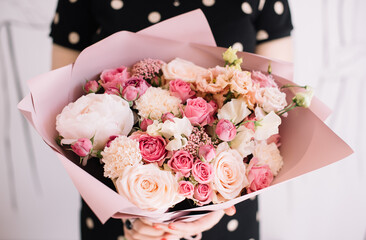 Very nice young woman holding big and beautiful bouquet of fresh peony, roses, carnations, eustoma flowers in tender pink colors, cropped photo, bouquet close up - 530225701