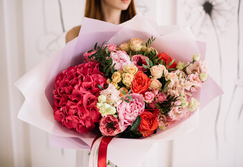 Very nice young woman holding big and beautiful bouquet of fresh hydrangea, peony, roses, eustoma
pistachio flowers in pink and red colors, cropped photo, bouquet close up - 530225727