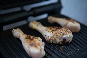 Cooking chicken legs on an electric grill, on the balcony of the apartment