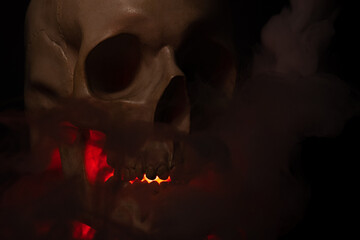 A skull with a jaw illuminated by red light and smoke coming out of it. An ominous look that...
