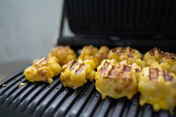 Cauliflower fried in an egg on an electric grill